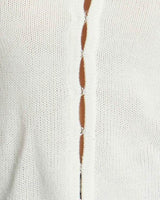 Close-up of a white knit Michelle vest featuring a vertical row of delicate silver hook-and-eye closures.