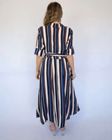 Back view of a midi dress with navy, cream, and burgundy vertical stripes, featuring a collar and a tie-waist detail.
