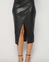 Black vegan leather midi skirt with a flattering wrap-front design and a high leg slit.