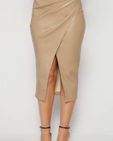 Latte-colored vegan leather midi skirt featuring a flattering wrap-front design and a front slit.