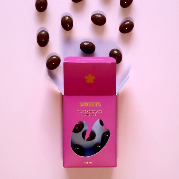 Pink box with black jelly beans on a pink background