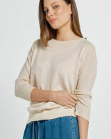 Woman wearing a cream-colored Morris sweater with a classic neckline, soft knit texture, and ribbed cuffs.
