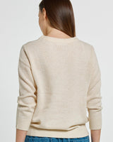 Back view of a woman wearing a cream-colored Morris sweater with a classic neckline and ribbed hem.