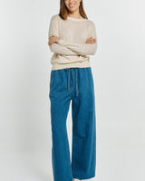 Woman wearing a cream-colored, relaxed-fit Morris sweater with a classic neckline and ribbed hem.