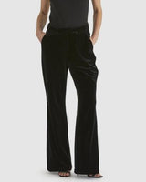 Black stretch velvet pants with a slight flare leg, fly front, and tab closure worn with a black top.