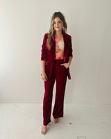 Woman wearing deep red wide-leg velvet pants with a matching blazer and floral top.