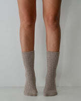 Taupe cable-knit wool and cashmere blend socks worn on legs, featuring a soft, textured design.
