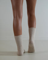 Beige cable knit wool and cashmere blend socks worn on legs, featuring a textured, lightweight design.