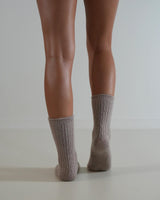 Beige cable knit socks made from a soft wool and cashmere blend, worn on legs against a neutral background.