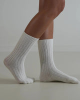 White ribbed wool and cashmere blend socks worn on feet, featuring a soft, textured knit design.