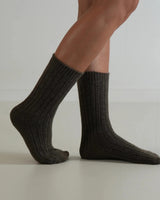 Dark charcoal grey ribbed wool and cashmere blend socks worn on feet, featuring a classic textured knit design.