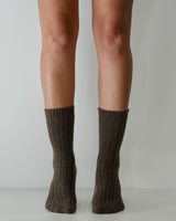 Chocolate brown ribbed wool and cashmere blend socks worn on legs, featuring a soft, textured knit design.