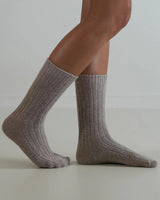 Beige ribbed wool and cashmere blend socks worn on feet, featuring a soft, textured knit design for everyday warmth.