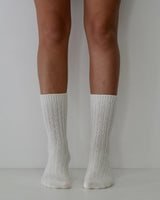 Milk-colored ribbed wool and cashmere blend socks worn on legs, featuring a soft, textured knit design.