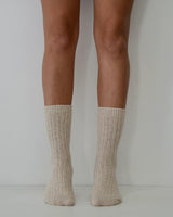 Natural ribbed wool and cashmere blend socks worn on legs, featuring a soft, textured knit design.
