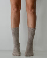Taupe ribbed wool and cashmere blend socks worn on legs, featuring a soft, textured knit design.