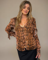 Woman wearing a sheer, brown patterned Odette ruffle blouse with button-down front and included camisole.