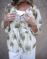Sage green palm print blouse with a tie-front detail, flutter sleeves, and lightweight Tencel-viscose fabric.