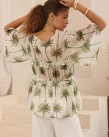Sage green palm print Tencel-viscose blouse with flutter sleeves, V-neckline, and tiered ruffle detailing.