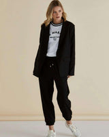 Relaxed fit black blazer with a single-button closure, classic collar, and front welt pockets worn over a white tee.