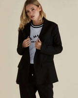 Model wearing a relaxed-fit black Portland blazer with a classic collar, lapels, and front welt pockets.