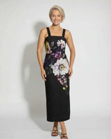 A woman wearing a black, sleeveless cotton-nylon Providence midi dress featuring a vibrant floral print.