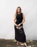 Model wearing a black Providence midi skirt featuring a large floral print, paired with a matching sleeveless top.