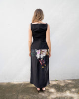 Woman wearing a black Providence skirt with a vibrant floral print panel, styled with a matching black sleeveless top.