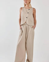 Beige button-front wrap vest with subtle stripes and a curved hem, paired with matching wide-leg trousers.