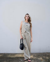 Woman wearing beige Renee paper bag pants with thin stripes, elasticated waistband, and side pockets.