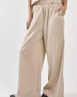 Beige Renee paper bag pants with a cinched elasticated waistband, button detail, and subtle vertical stripe texture.