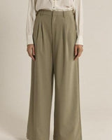 Sage green relaxed-fit trousers with front pleats, zip fly, and wide-leg silhouette.