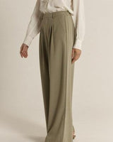 Sage green relaxed-fit trousers featuring front pleats, side pockets, and a tailored silhouette.