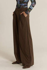 Relaxed fit chocolate brown trousers featuring front pleats, side pockets, and a tailored silhouette.