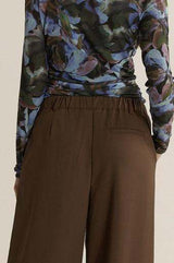 Back view of chocolate brown relaxed-fit trousers featuring an elasticated waist and tailored pocket detail.