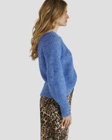 Fluffy blue oversized cardigan with a ribbed round neckline and button-front closure worn with a leopard print skirt.