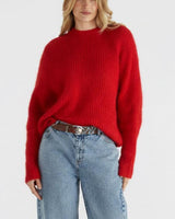 Oversized red fluffy knit sweater with a ribbed neckline and dropped shoulders, styled with blue denim jeans.