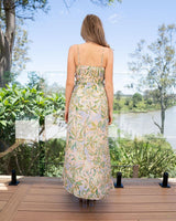 Back view of a woman wearing a lightweight, floral print rayon maxi dress with spaghetti straps and a smocked bodice.