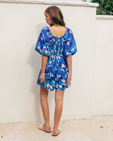 Blue and white floral print playsuit with puff sleeves and a shirred back panel, worn by a woman standing outdoors.