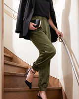High-rise pesto satin pants with a gathered blouson leg and cuffed ankle, styled with a black blazer and heels.