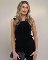 Woman wearing a black sleeveless knit vest with a button-up front, crew neckline, and ribbed texture.