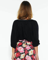 Back view of a black Showcase top with three-quarter sleeves and white stitch detailing on the neckline.