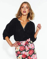 Black Showcase top in a viscose-linen blend featuring a V-neckline with white whipstitch detailing and puff sleeves.
