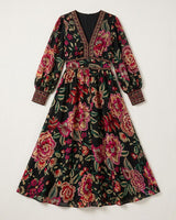 Black maxi dress with vibrant floral print, V-neckline, long sleeves, and intricate border detailing.