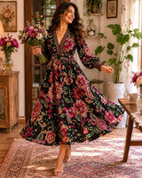 Woman wearing a black floral maxi dress with a V-neck, long sleeves, and intricate border detailing in a bohemian style.