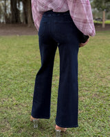Dark blue straight-leg stretch jeans with a mid-rise fit and back pockets, worn with a pink plaid shirt outdoors.