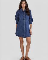 Model wearing a dark blue denim shacket dress with long sleeves, silver button details, and a front patch pocket.