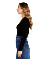 Woman wearing a black long-sleeve rib knit sweater with a Johnny collar, styled with blue denim jeans.