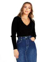 Woman wearing a black long-sleeve rib knit sweater with a Johnny collar, paired with a blue denim skirt.
