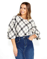 Woman wearing a black and white plaid Valentina bias blouse with long sleeves and a high neckline.